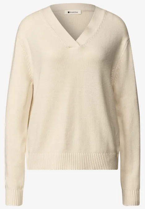 Beiger Strickpullover mit V-Ausschnitt, langen Ärmeln und Rippbündchen an Saum und Ärmeln.
