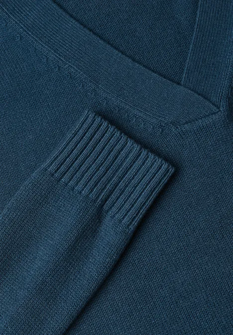 Nahaufnahme eines dunkelblauen Strickpullovers mit V-Ausschnitt und Rippbündchen am Ärmel.