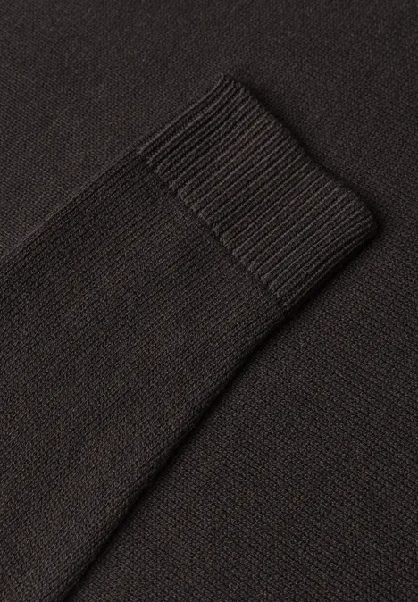Nahaufnahme eines schwarzen Strickpullover-Ärmelbündchens mit geripptem Stoff.