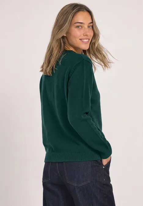 Langarm Pullover mit Boat Neck shadow teal Frau in grünem Pullover und Jeans, seitlich stehend, lächelt in die Kamera.
