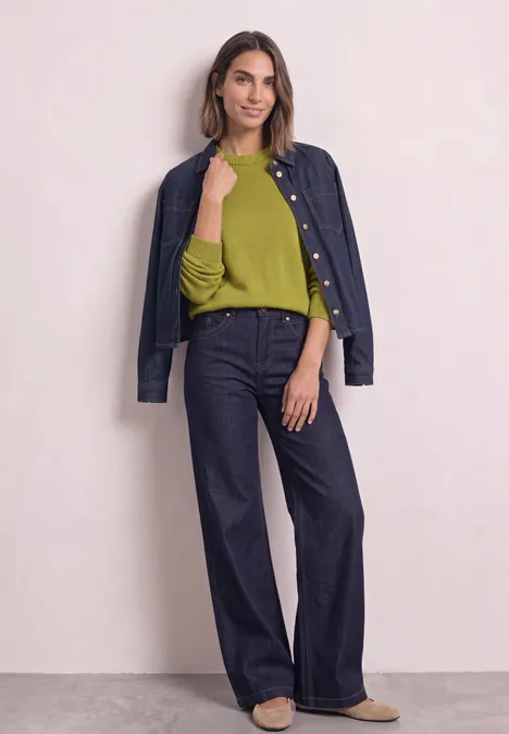 Langarm Pullover mit Boat Neck apple lime Dame mit grüner Bluse und dunkelblauer Jeansjacke über den Schultern, weiten Jeanshose vor rosa Hintergrund.