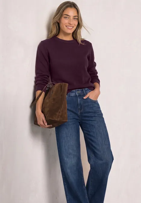 Langarm Pullover mit Boat Neck berry maroon Junge Frau in lila Pullover und weitem Jeans, lächelnd vor weißem Hintergrund, mit brauner Tasche am Arm.