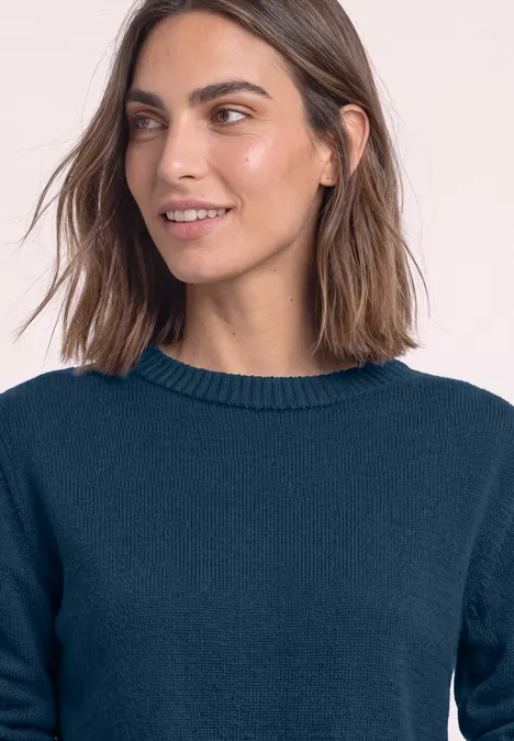 Langarm Pullover mit Boat Neck blue petrol Junge Frau mit schulterlangen braunen Haaren und dunkelblauem Pullover lächelt leicht seitlich.