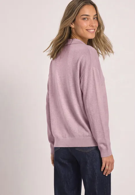 Langarm Pullover mit Polokragen quiet rose mel. Frau in rosa Pullover und dunklen Jeans blickt lächelnd über die Schulter vor weißem Hintergrund.