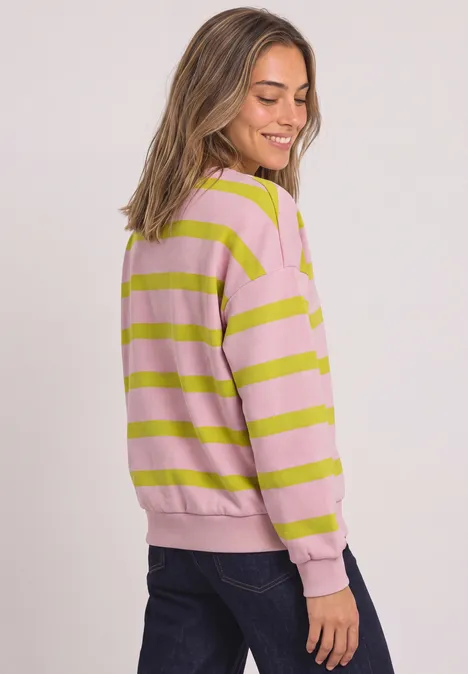 Sweatshirt mit Rundhals und Streifen apple lime Frau im rosa-grün gestreiften Pullover und dunkler Jeans, seitlich stehend und lächelnd.