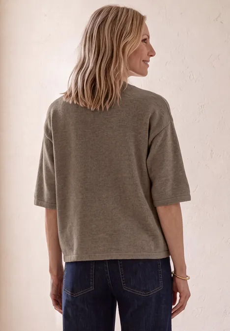3/4-Arm Pullover mit Rundhals sanded amber mel. Frau von hinten in grauem, lockerem Oberteil und blauen Jeans vor hellem, neutralem Hintergrund.