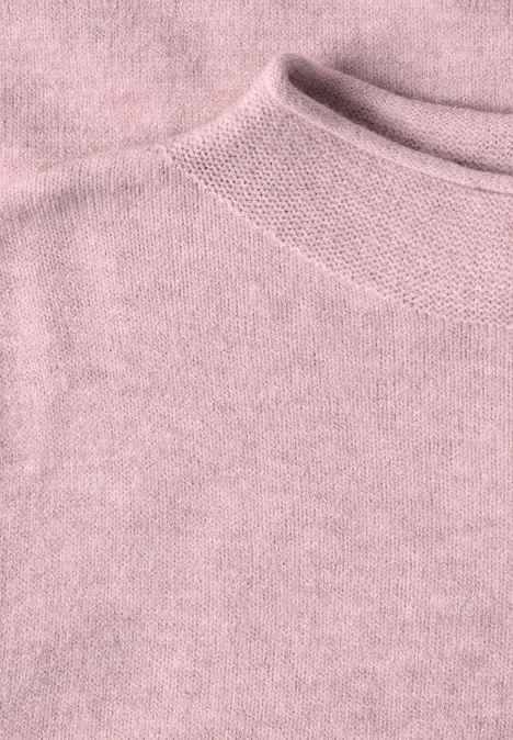 Nahaufnahme eines rosafarbenen Strickpullovers mit feiner Textur und Rippenstrick am Kragen.