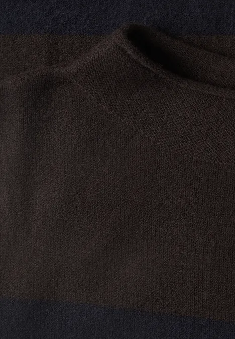 Nahaufnahme eines dunkelbraunen, grob gestrickten Stoffes mit rundem Halsausschnitt.