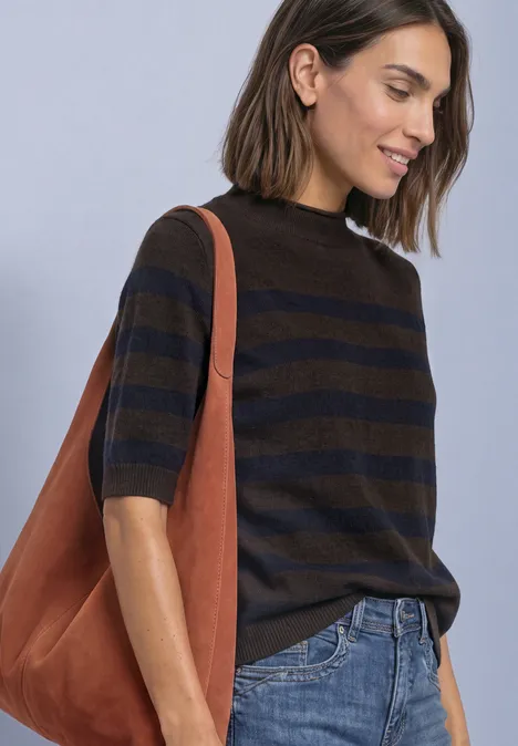 Frau in gestreiftem Kurzarm-Pullover, Jeans und großer brauner Ledertasche über der Schulter.