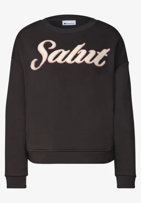 Schwarzer lässiger Pullover mit dem Aufdruck 'Salut' in auffälliger Schrift auf der Vorderseite.