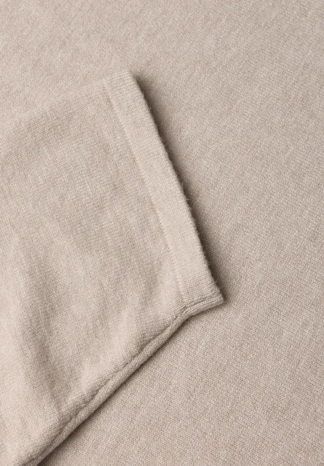 Nahaufnahme eines beigen Stoffes mit eingenähter Tasche.