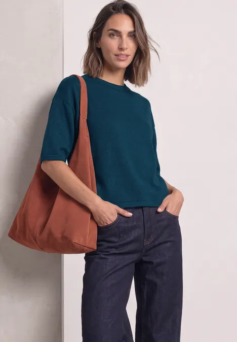3/4-Arm Pullover mit Rundhals blue petrol mel. Eine Frau trägt ein dunkelblau-grünes Shirt, dunkle Jeans und eine orangefarbene Tasche über der Schulter.