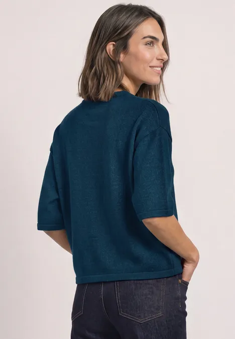 3/4-Arm Pullover mit Rundhals blue petrol mel. Frau in 3/4-Ansicht mit kurzen dunklen Haaren, trägt einen petrolfarbenen Pullover und hat die Hände in Taschen.