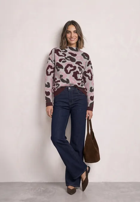 Trui met col en luipaardpatroon pure beige Frau trägt Leo-Pullover, dunkelblaue Schlagjeans und braune Tasche, dazu spitze Schuhe.