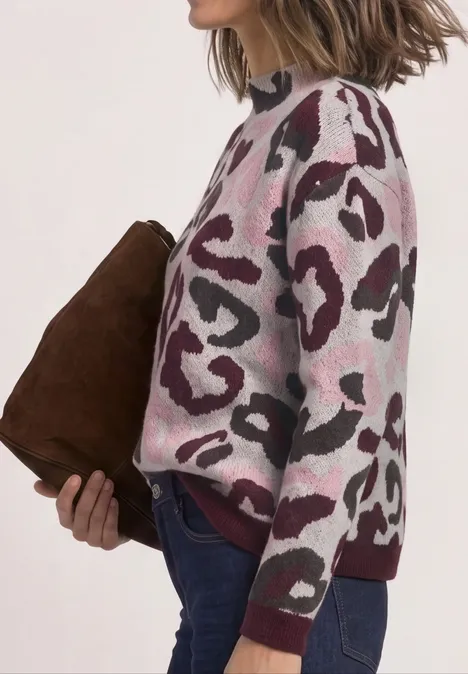 Trui met col en luipaardpatroon pure beige Seitliche Ansicht einer Person in rosa-weißem Leoparden-Pullover, Jeans, mit brauner Clutch.