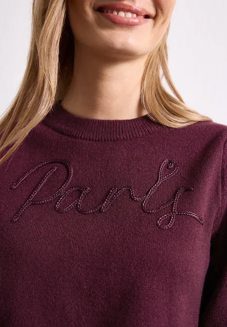 Femme en pull bordeaux avec l'inscription brodée 'Paris'.
