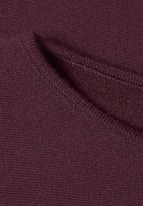 Nahaufnahme eines burgunderroten Strickstoffs mit einer kleinen Tasche oder Schlitz.