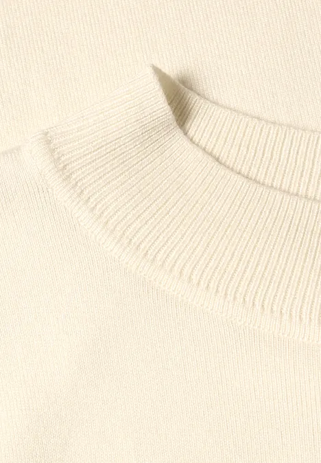 Nahaufnahme des schlichten, cremefarbenen Strickkragens eines Pullovers.