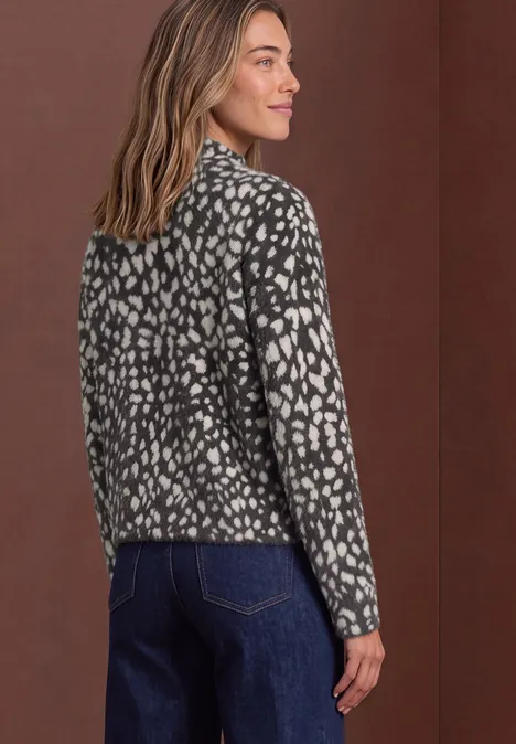 Pull en laine fine à motif jacquard black coffee Frau in gemusterter schwarz-weißer Jacke und Jeans, von hinten fotografiert.