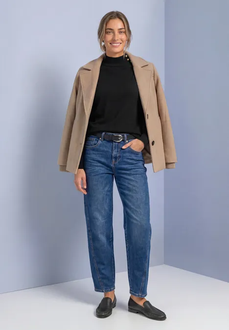 Pullover mit Turtle Neck und Knopfdetails Black Frau mit schwarzem Rollkragenpullover, blauer Jeans und beigem Blazer lässig posierend.