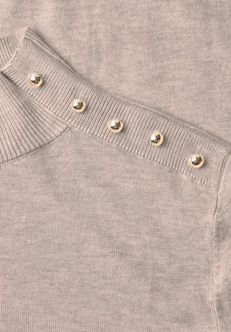 Beiges Strickoberteil mit Rippenmuster und einer Reihe goldener Knöpfe an der Schulter
