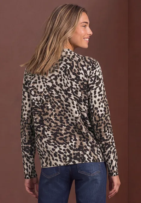 Rückansicht einer Frau in einem langärmligen Leopardenmuster-Shirt und Jeans vor braunem Hintergrund.