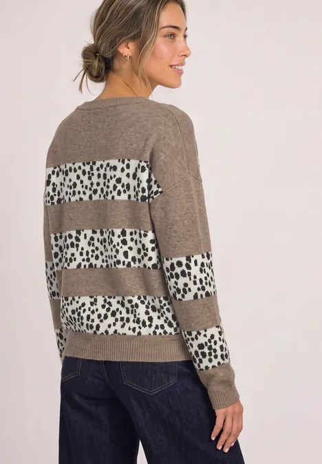 Femme portant un pull marron avec bandes blanches à pois bruns dans le dos