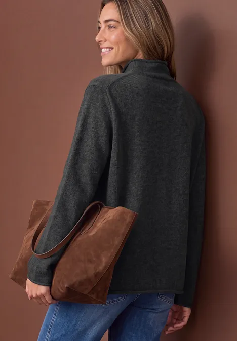 Pullover mit Turtle Neck und Rollkanten armor grey mel. Frau in grauer Jacke mit brauner Wildledertasche, lächelnd über die Schulter blickend.
