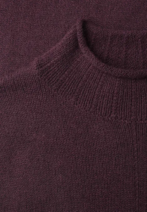 Pull à col roulé et bords roulés berry plum mel. Nahaufnahme eines weinroten, fein gestrickten Pullovers mit geripptem Rundhalsausschnitt.