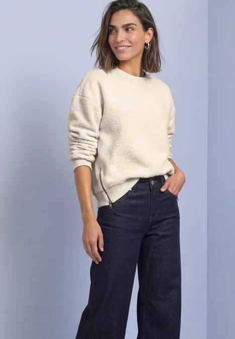 Teddy-Sweatshirt mit Zipperdetails pure beige Eine Frau trägt einen hellen Pullover und dunkle Jeans vor neutralem Hintergrund.