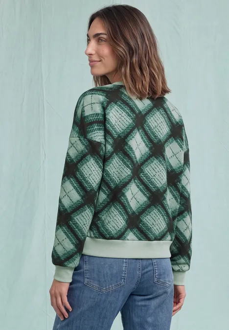 Sweat-shirt à col rond et motif à carreaux stormy green Femme de dos en jean et pull vert à carreaux sur fond clair.