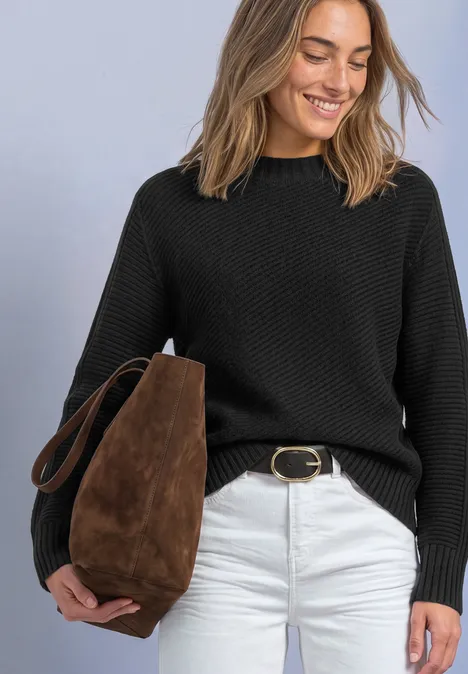 Langarm Pullover mit Turtle Neck und Struktur armor grey mel. Frau mit schwarzem Strickpullover, weißer Hose und brauner Suede-Tasche, lächelt und blickt nach unten.