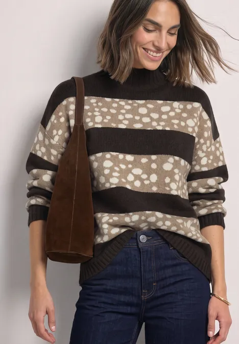 Jacquard Pullover mit Turtle Neck black coffee mel. Frau in gestreiftem Pullover mit beige-braunen Punkten, dunkler Hose und brauner Schultertasche, lächelnd.