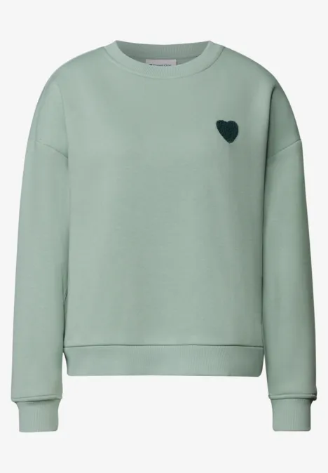 Loose Fit Sweatshirt mit Patch Detail eucalyptus green Ein mintgrüner Pullover mit kleinem schwarzen Herz auf der Brust.