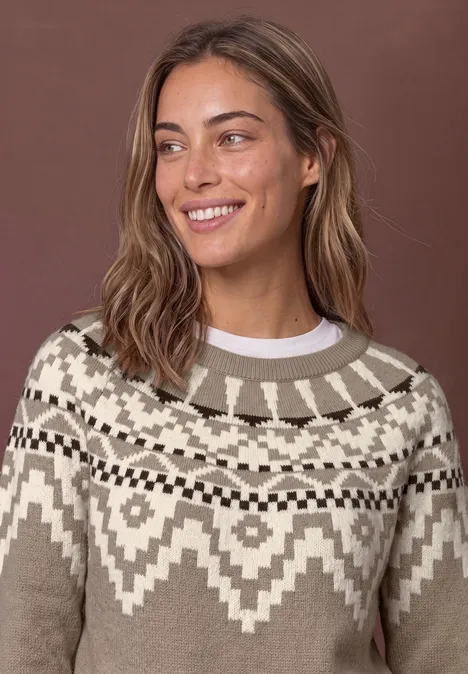 Pullover mit Rundhals und Jacquardmuster sanded amber Eine lächelnde Frau mit schulterlangem Haar trägt einen beigefarbenen Pullover mit weißem Norwegermuster.