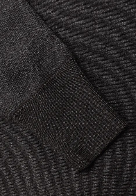 Nahaufnahme eines dunklen Strickärmels mit Bündchen.