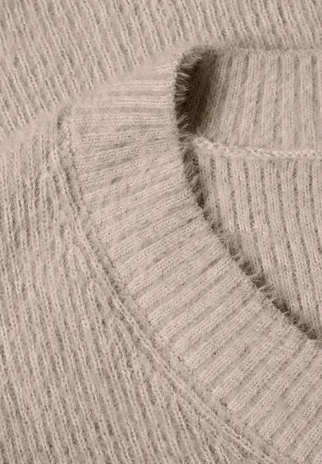 Nahaufnahme eines hellbeigen, gerippten Strickpullovers