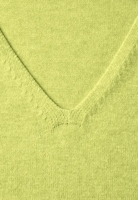 Gros plan d’un col en V en maille vert pastel.