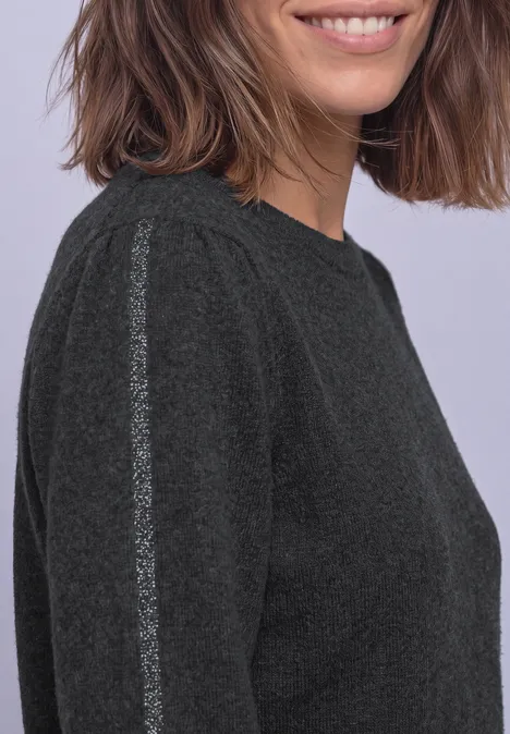 Pullover mit Rundhals und Glitzertape armor grey mel. Eine Frau mit schulterlangem braunem Haar trägt einen dunkelgrauen Pullover mit silbernem Schulterstreifen.