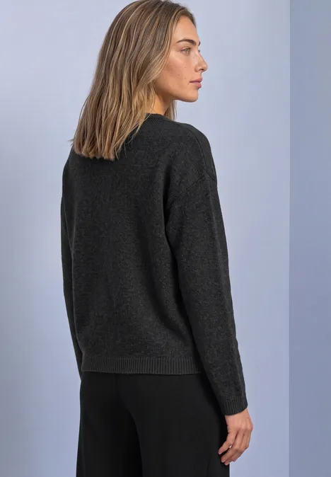 Pullover mit Boat Neck und Broschendetail armor grey mel. Seitliche Ansicht einer Frau in schwarzem Pullover und Hose, vor hellem Hintergrund.
