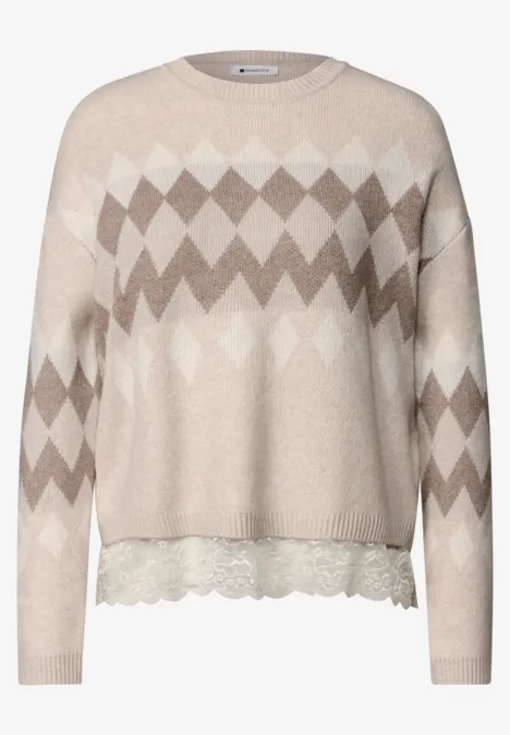 Beiger Pullover mit Rautenmuster und Spitzenbesatz am Saum.