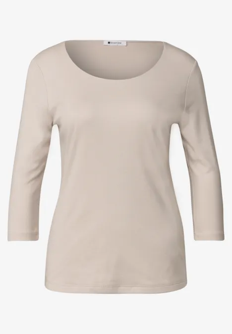 Un t-shirt féminin beige à manches trois-quarts et encolure ronde, style épuré.
