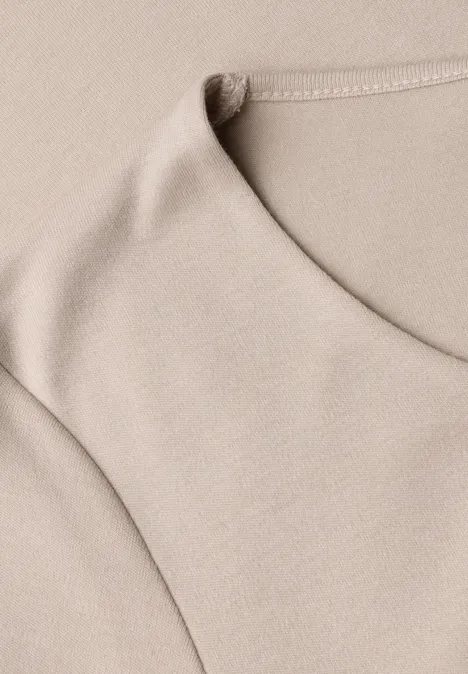 Haut beige sans manches en tissu doux, gros plan sur la texture coton.