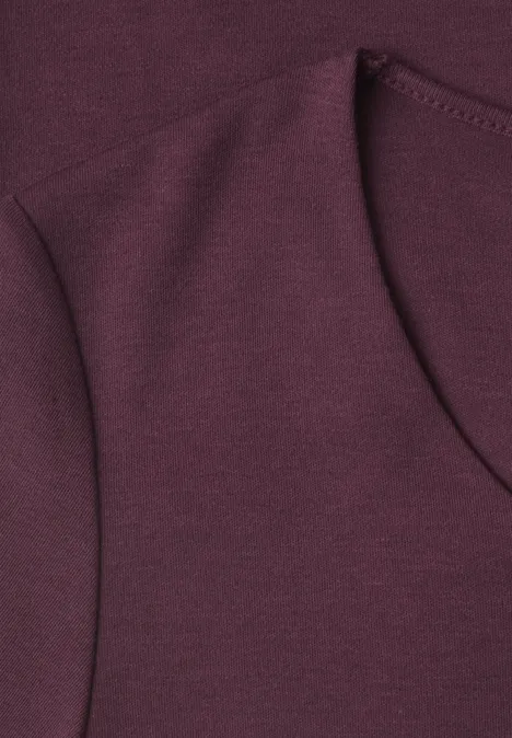 Gros plan sur un tissu de sweat-shirt bordeaux avec coutures apparentes