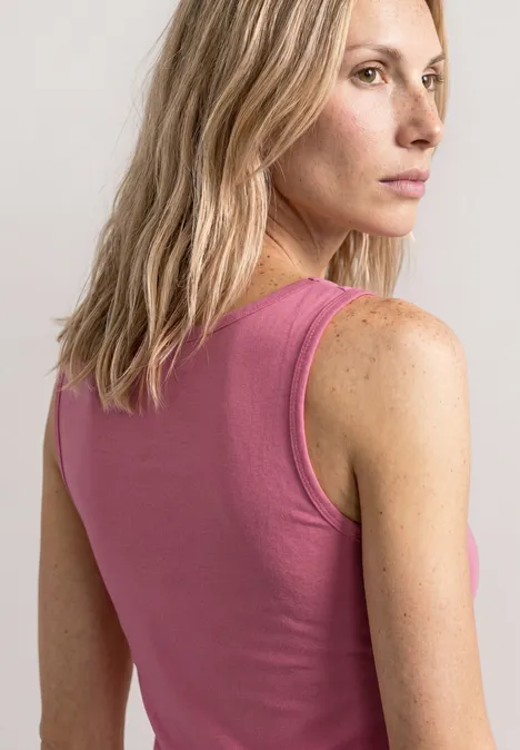Vrouw met blond haar van achteren in een mouwloze roze top