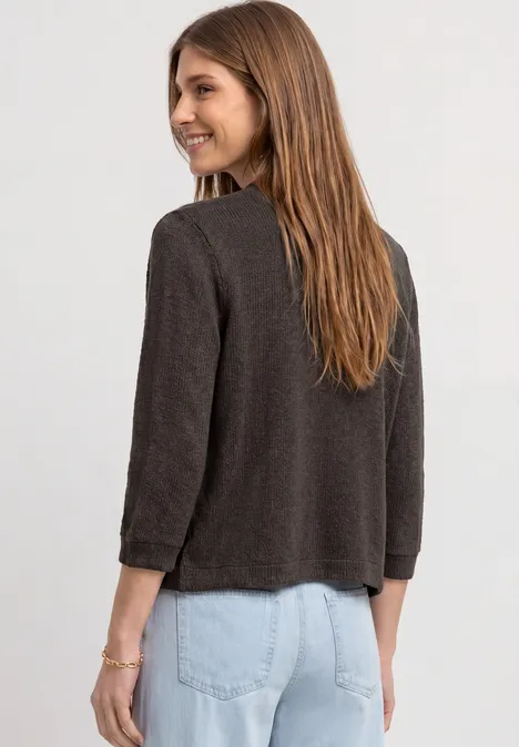 Vrouw van achteren in een bruine jas en lichtblauwe spijkerbroek.