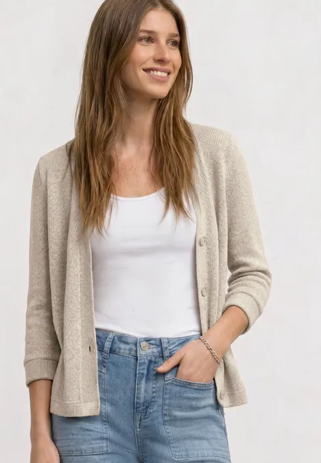 Vrouw met een wit hemdje, een beige vest en een blauwe jeans.