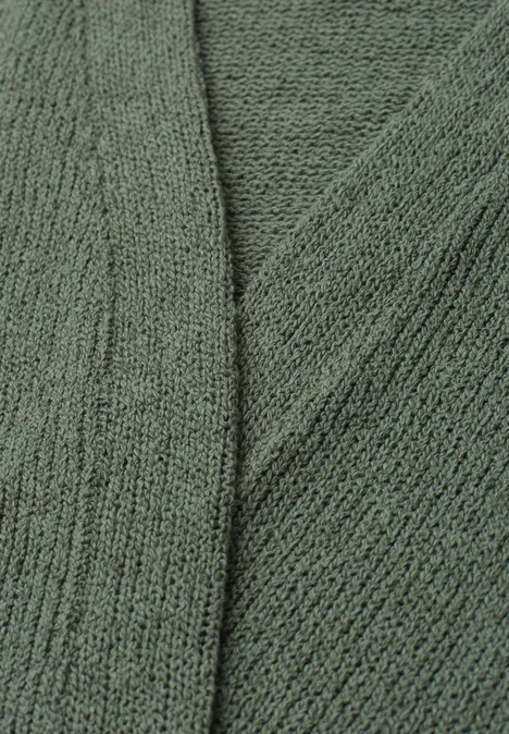 Gros plan sur un tissu tricoté vert à la texture douce et au motif de mailles fines.