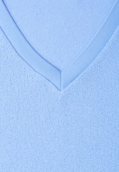 Close-up van een lichtblauwe V-hals van fijngebreide stof.