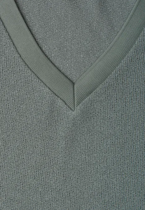 Close-up van een grijze V-hals van fijne gebreide stof met subtiele structuur.